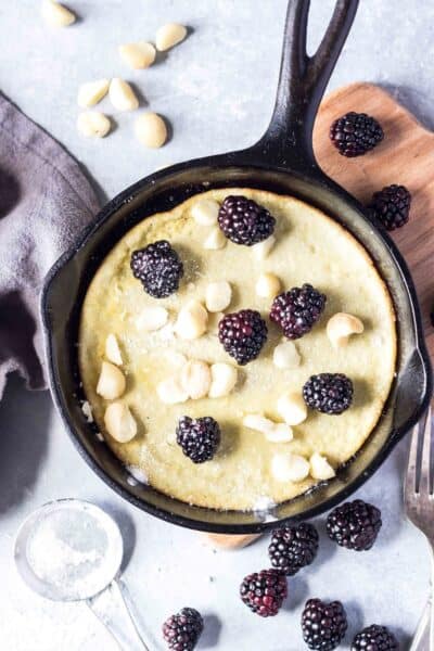 Keto Dutch Baby in skillet with blackberries and macadamia nuts