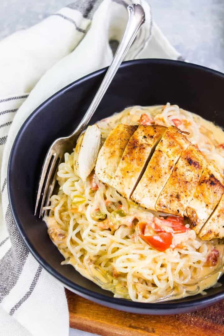 keto taco alfredo chicken pasta in a black bowl with a white striped tea towel to the side