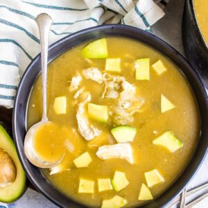 white chicken chili in a black bowl topped with diced avocado