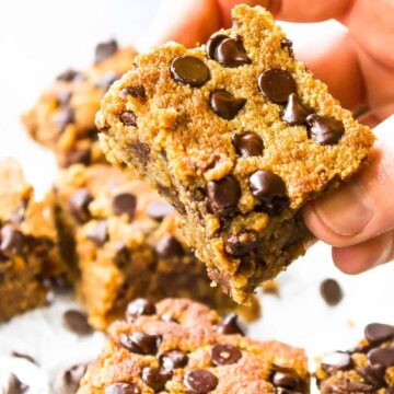 A single keto blondie being held above the rest of the batch.