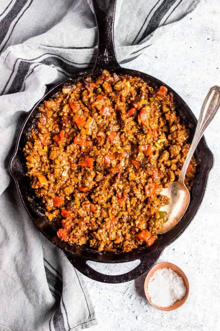 Keto Sloppy Joe mixture in a cast iron skillet with a serving spoon