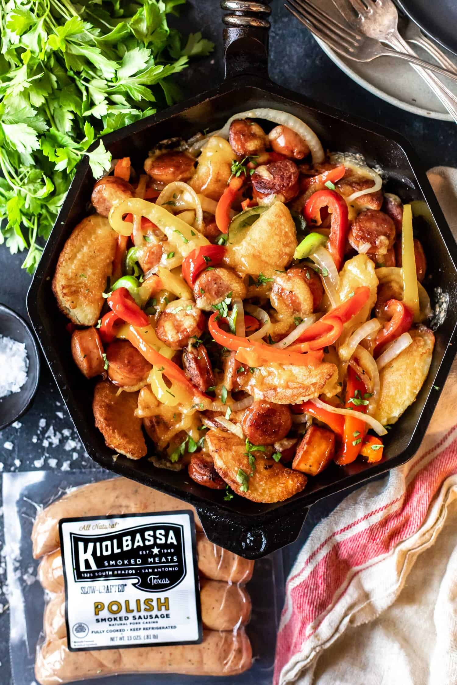 Cast Iron Skillet filled with cooked peppers, onions, rounds of sausage and keto pierogi's