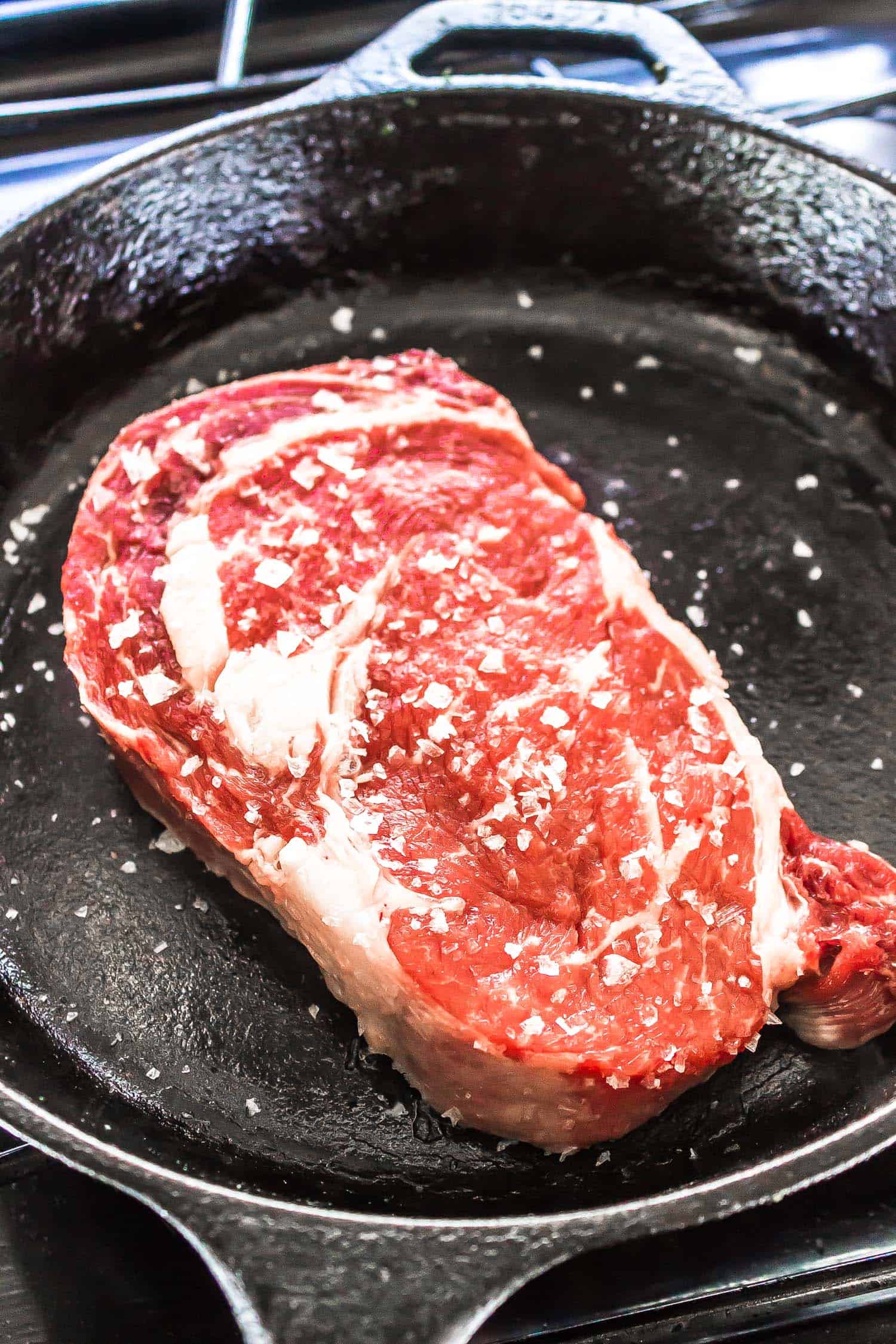 Cast Iron Steak being seasoned with salt