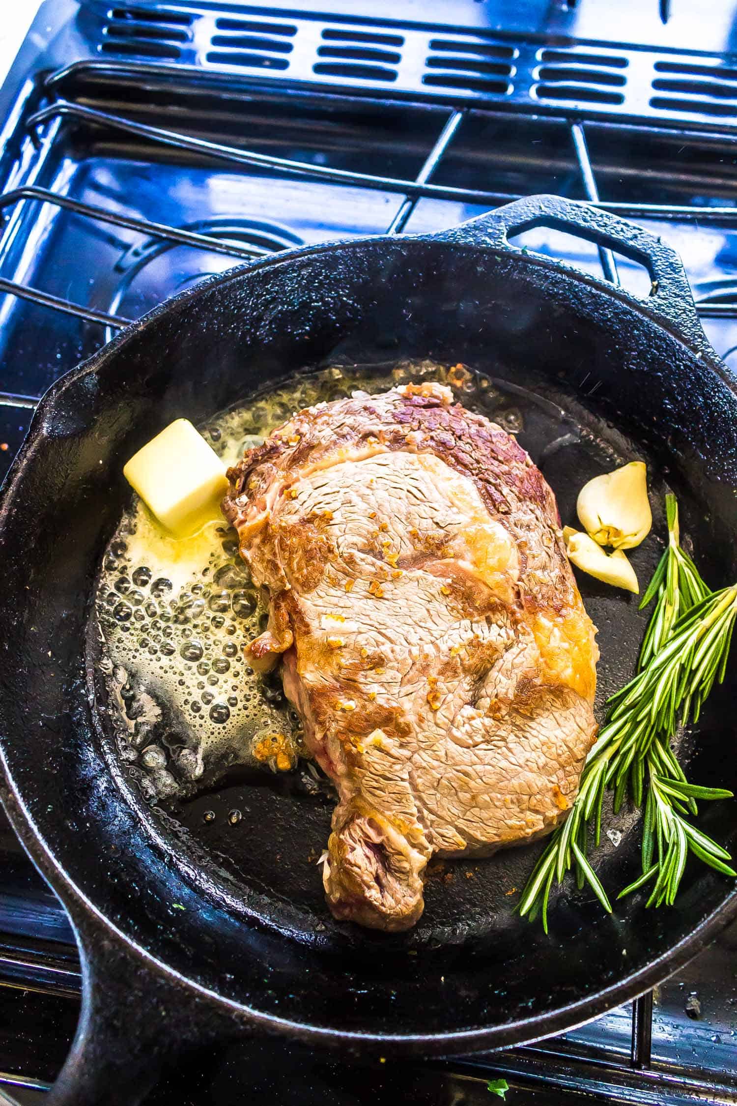Cast Iron Steak being seared with garlic, butter, and rosemary