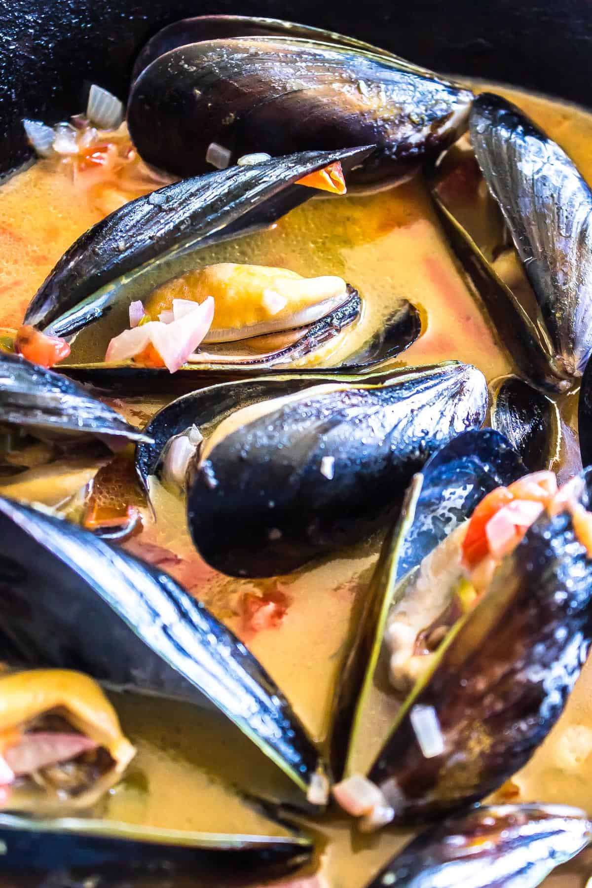 closeup image of Chilli Mussels simmering in a cast iron skillet