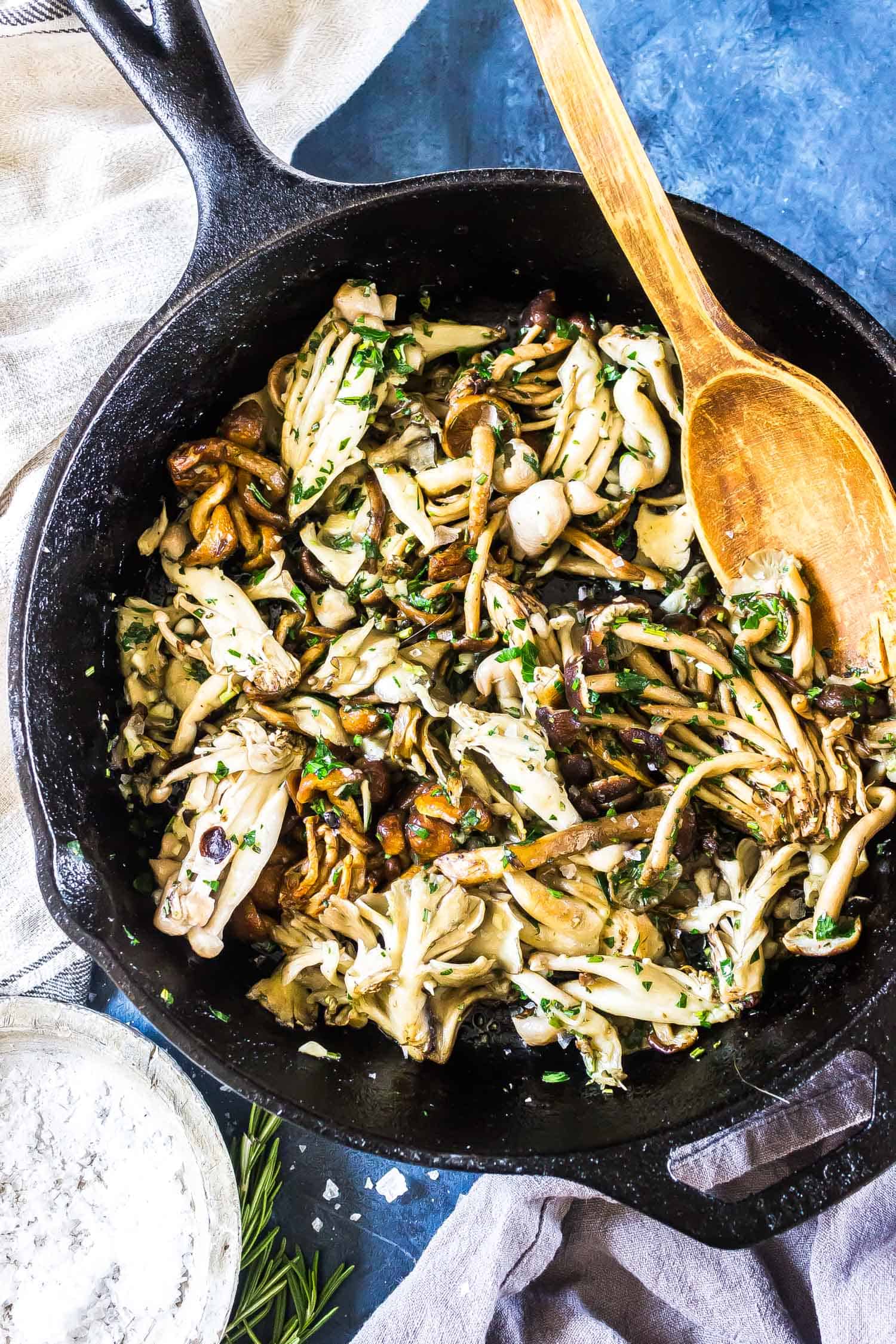 Garlic Butter Mushrooms in a cast iron skillet with a wooden spoon
