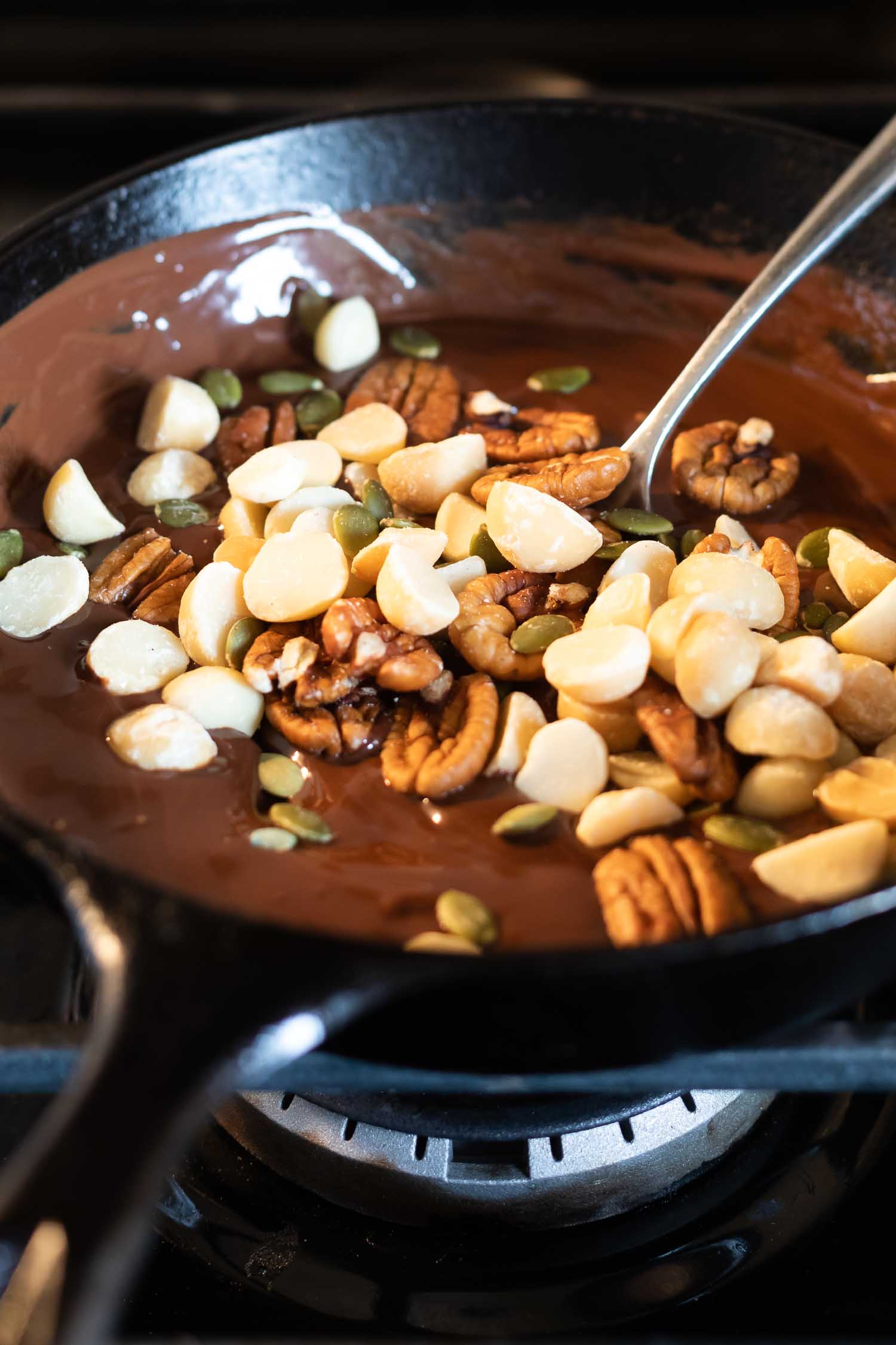 nuts, seeds, and chocolate in a cast iron skillet on the stove top