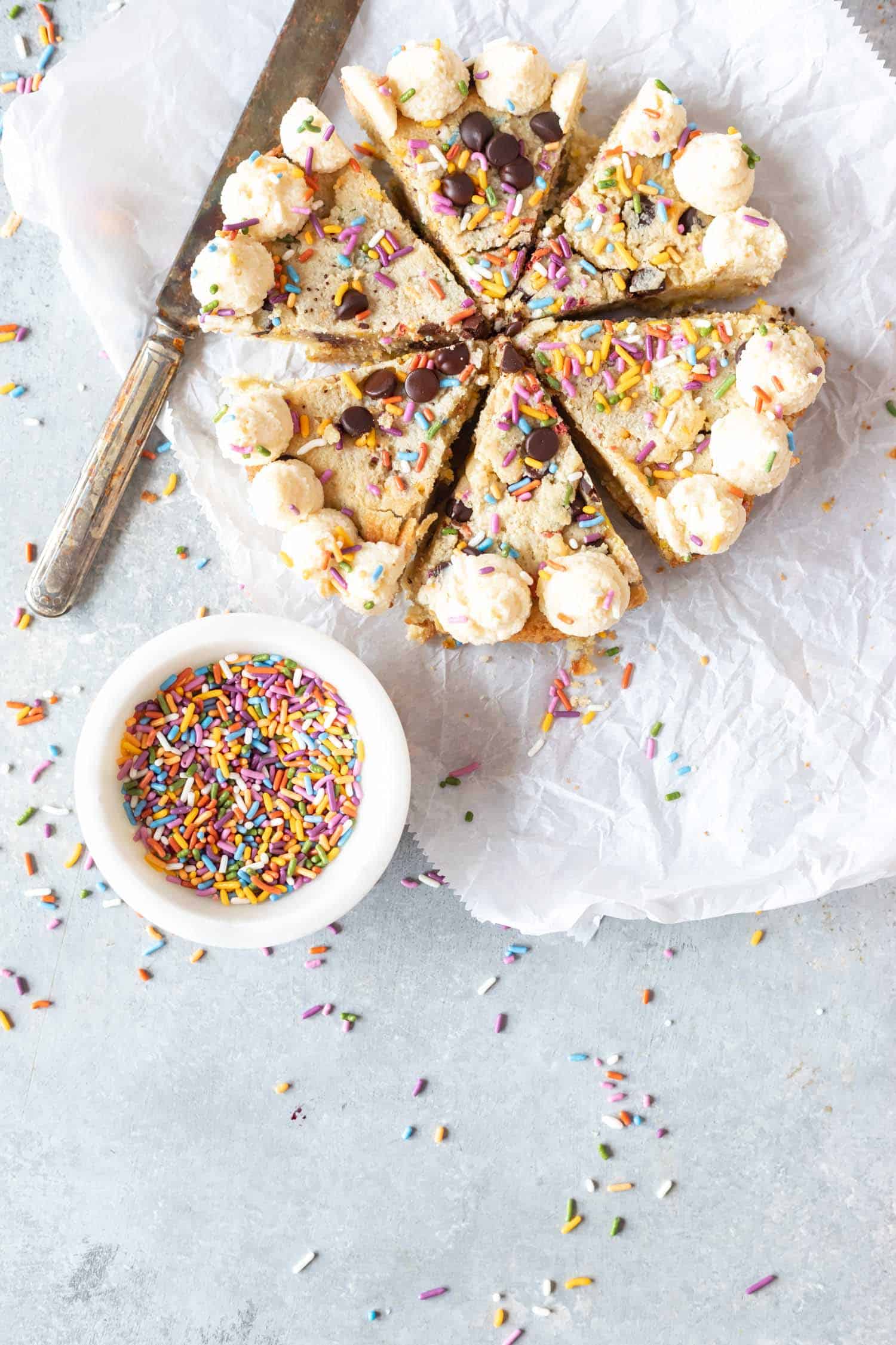 Keto Confetti Skillet Cookie on parchment with sprinkles scattered around