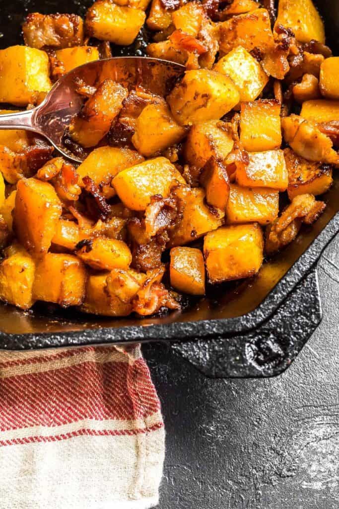 Roasted Butternut Squash in a cast iron skillet, a large serving spoon rests in the middle