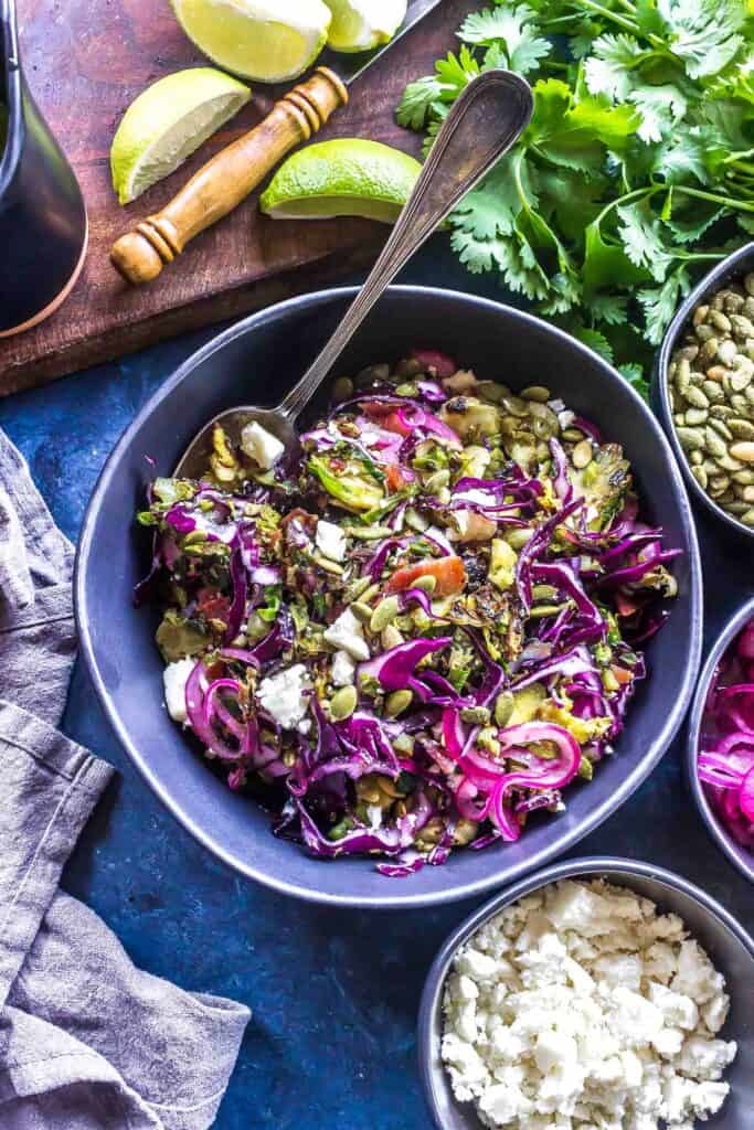 Keto Charred Brussels Sprout Salad with pepitas, bacon, cojita cheese, pickled red onions, and a creamy cilantro cojita dressing!