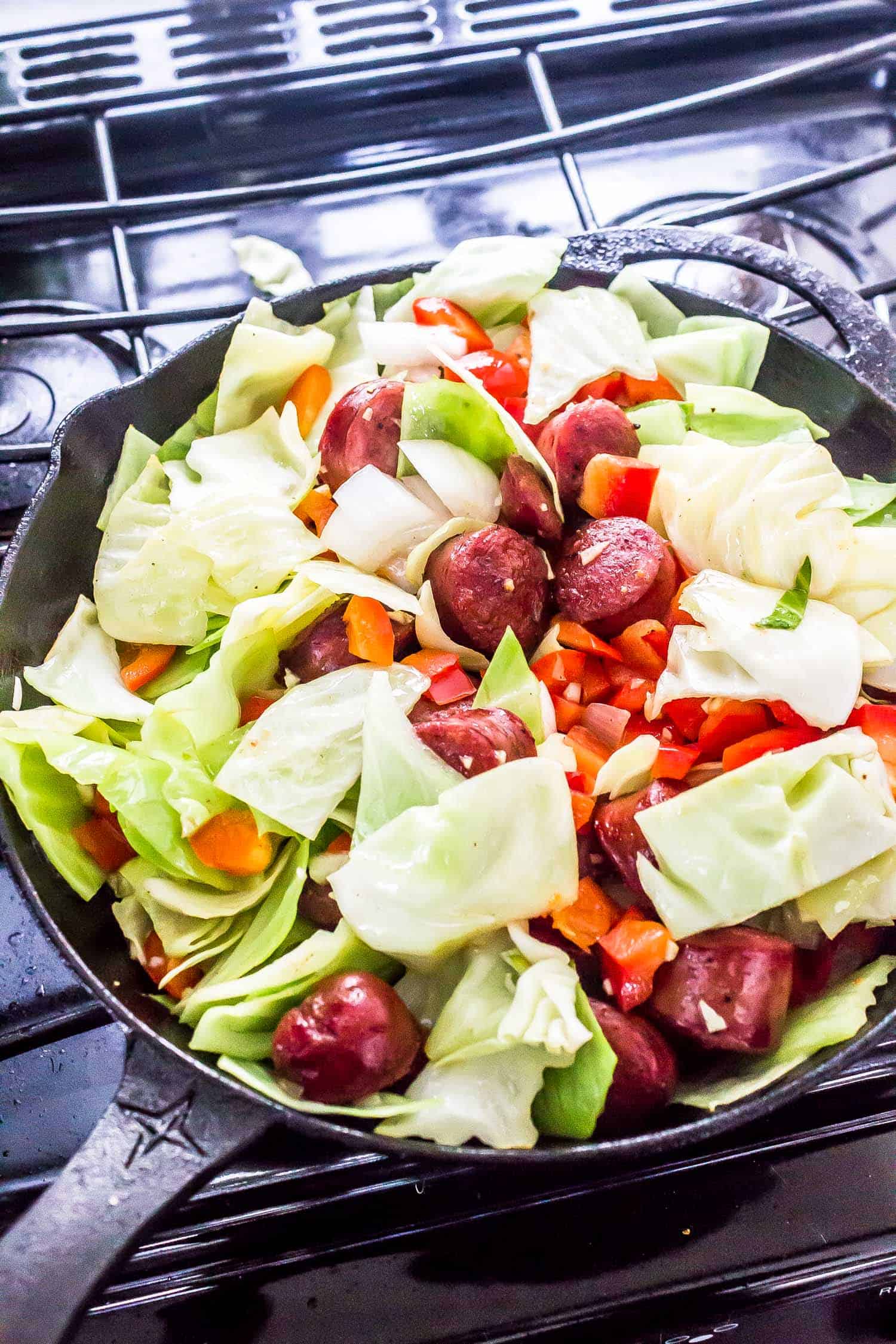 cabbage, tomatoes, bell peppers, and onions in a cast iron skillet