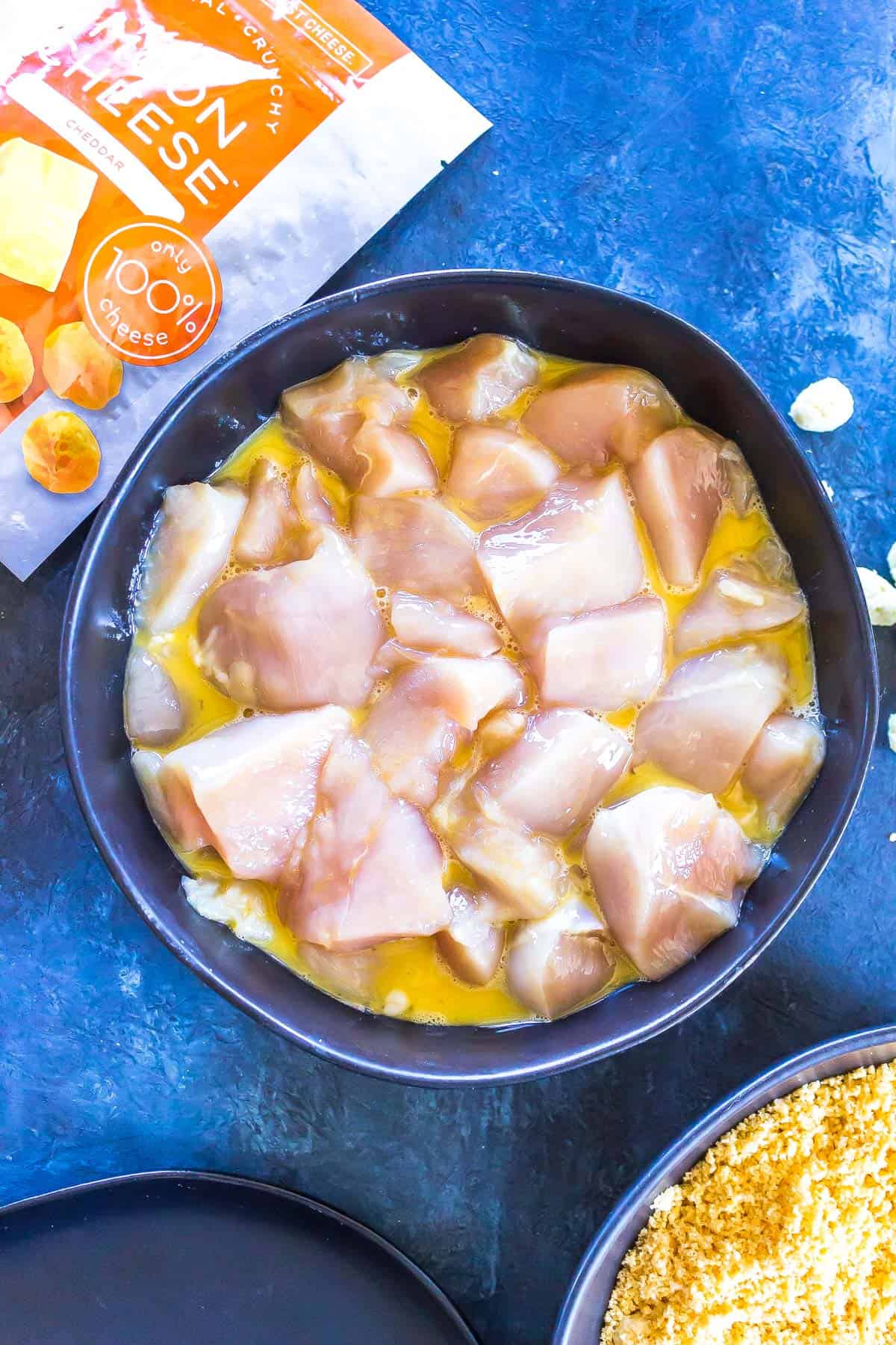 raw chicken cut into cubes in an egg wash.