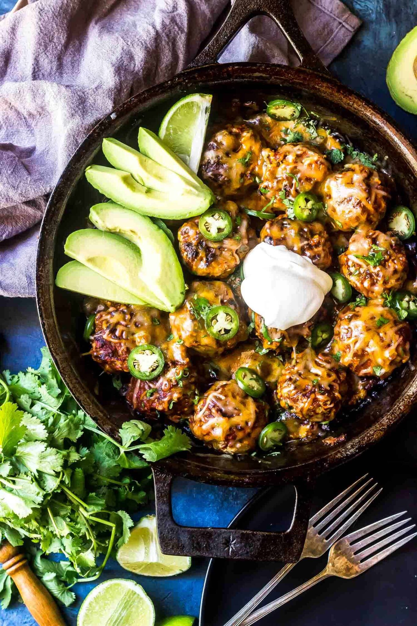 Keto Enchilada Meatball Skillet in skillet with avocado and sour cream on t...