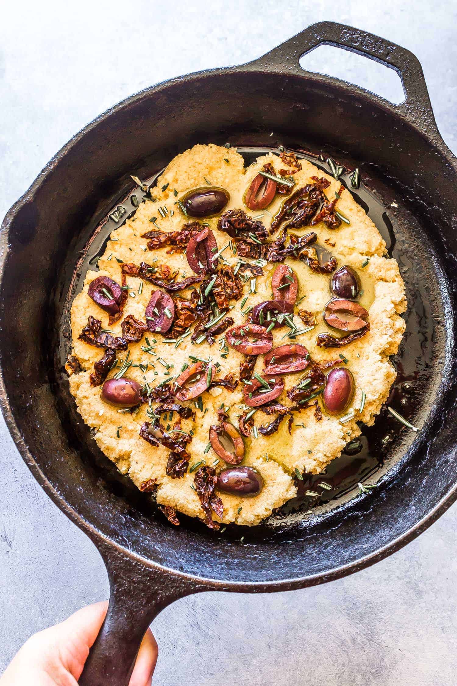 Keto Focaccia dough in skillet topped with olives and rosemary