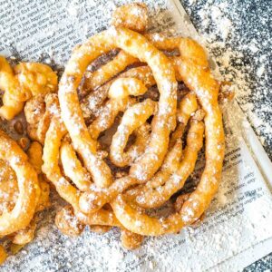 Keto Funnel Cake on a newspaper sprinkled with powdered erythritol