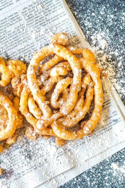 Keto Funnel Cake on a newspaper sprinkled with powdered erythritol