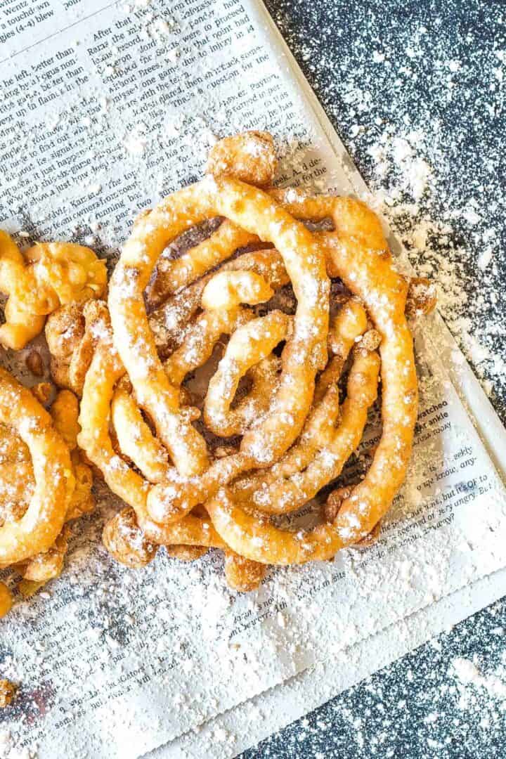 Keto Funnel Cake on a newspaper sprinkled with powdered erythritol