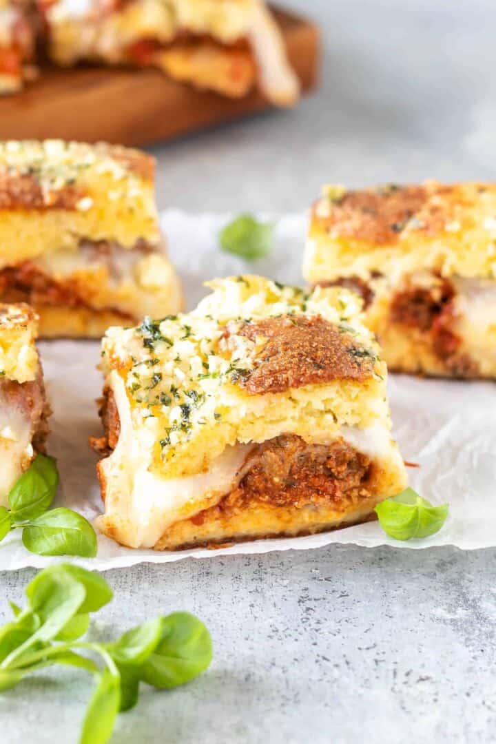 meatball sliders on white parchment paper with fresh basil scattered around