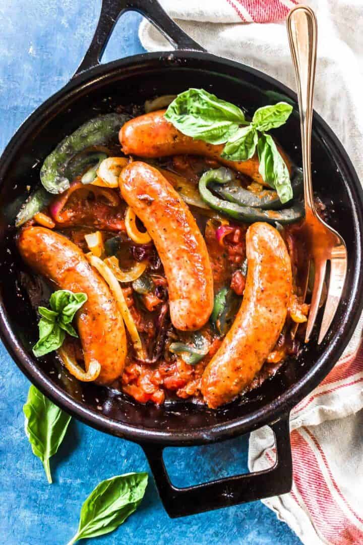 Keto Italian Sausage, Peppers, and Onions in a cast iron skillet with fresh basil.