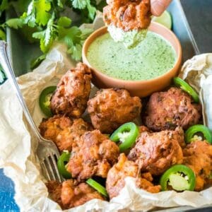 Keto Jalapeno Shrimp Hushpuppies on a tray, one hushpuppy is being dipped into the jalapeno sauce