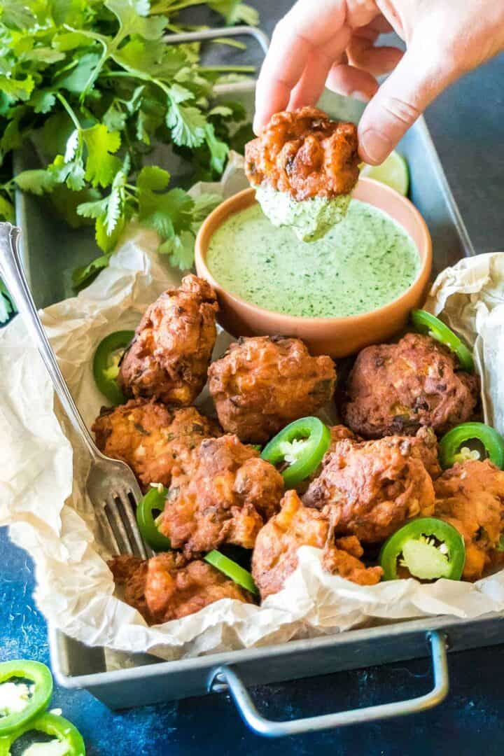 Keto Jalapeno Shrimp Hushpuppies on a tray, one hushpuppy is being dipped into the jalapeno sauce