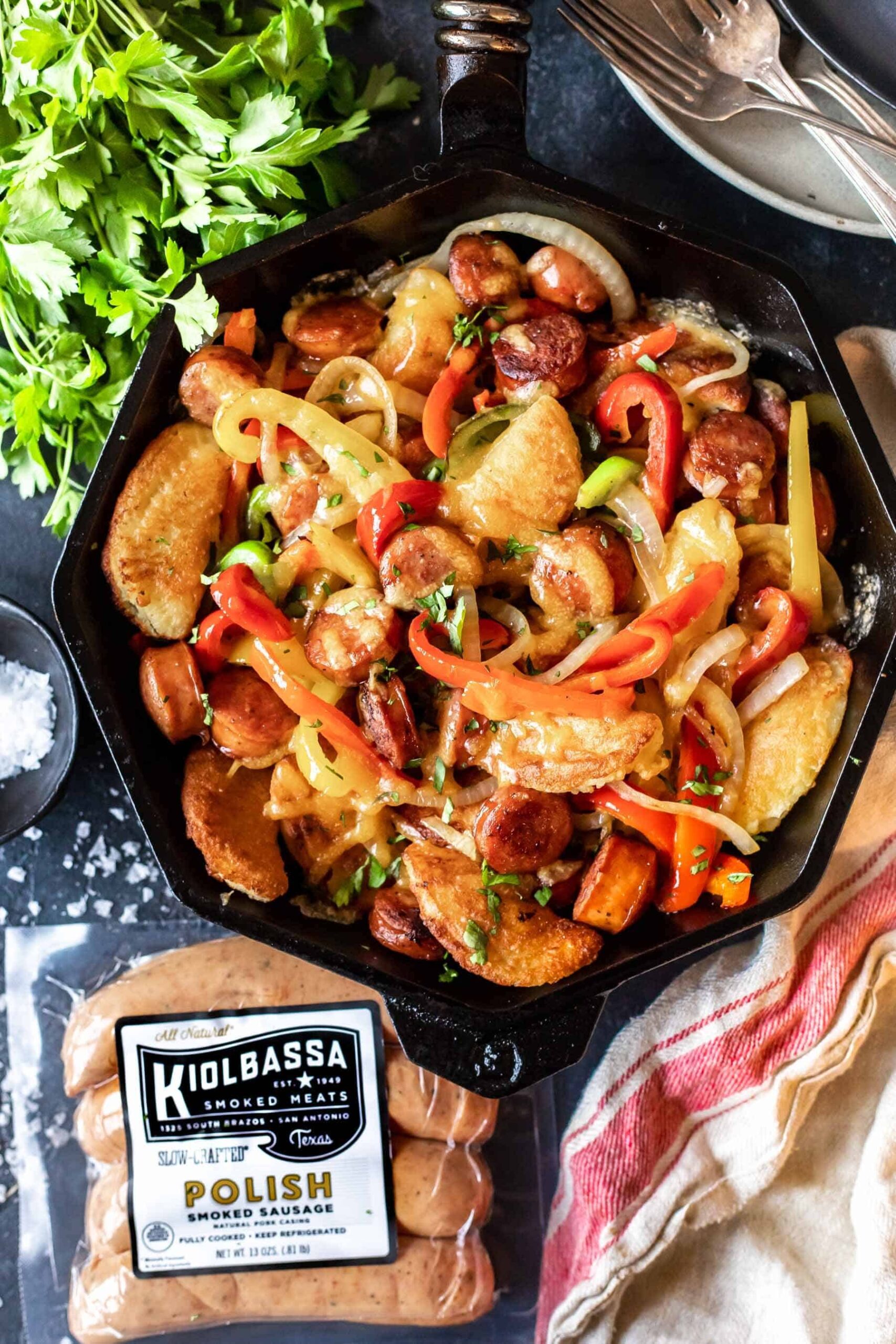 Cast Iron Skillet filled with cooked peppers, onions, rounds of sausage and keto pierogi's
