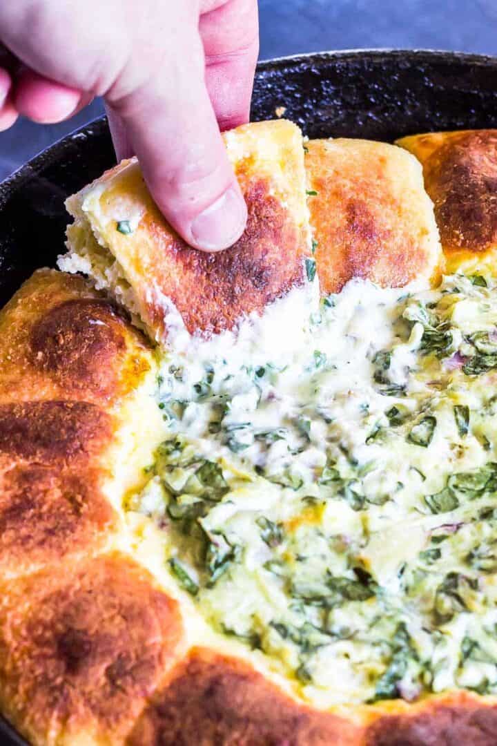 Keto Spinach Artichoke Dip Pull Apart Rolls with one being pulled out of skillet