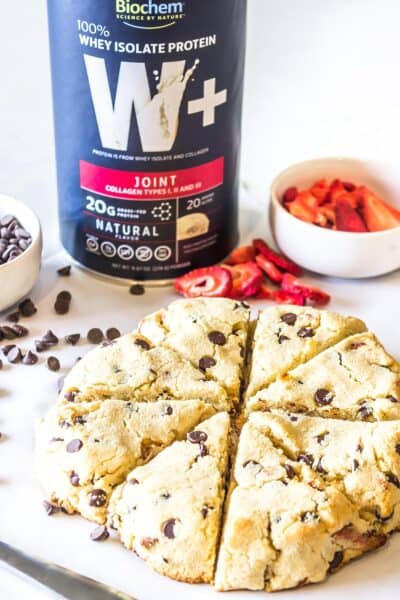Strawberry Chocolate Chip Scones flanked by chicolate chips and dehydrated strawberries with a Cannister of Biochem Whey protein isolate plus joint powder prominently featured