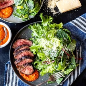 Steak and greens on a plate with romesco sauce