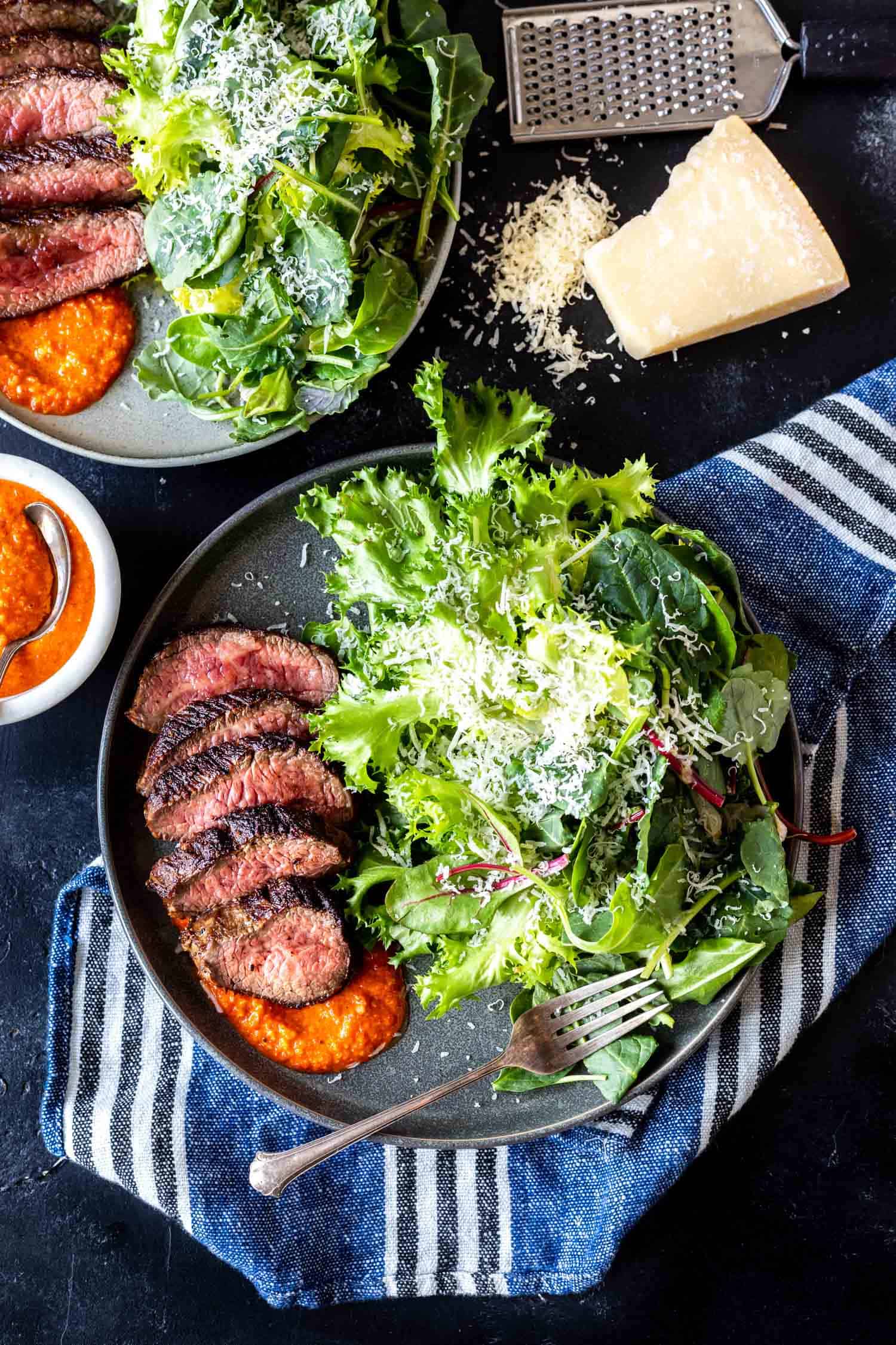 Steak and greens on a plate with romesco sauce