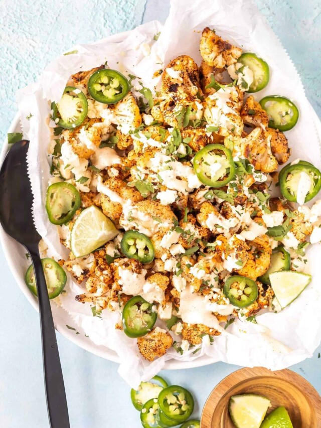 street style cauliflower on plate topped with cream, jalapenos, and lime