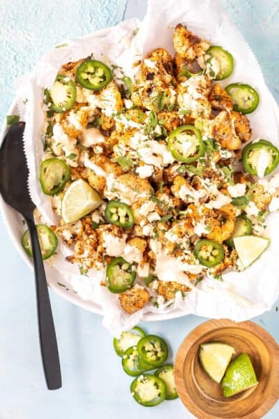 street style cauliflower on plate topped with cream, jalapenos, and lime