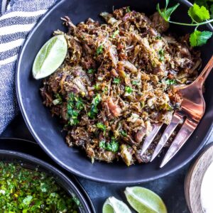 Authentic Carnitas Recipe - carnitas in a bowl with limes