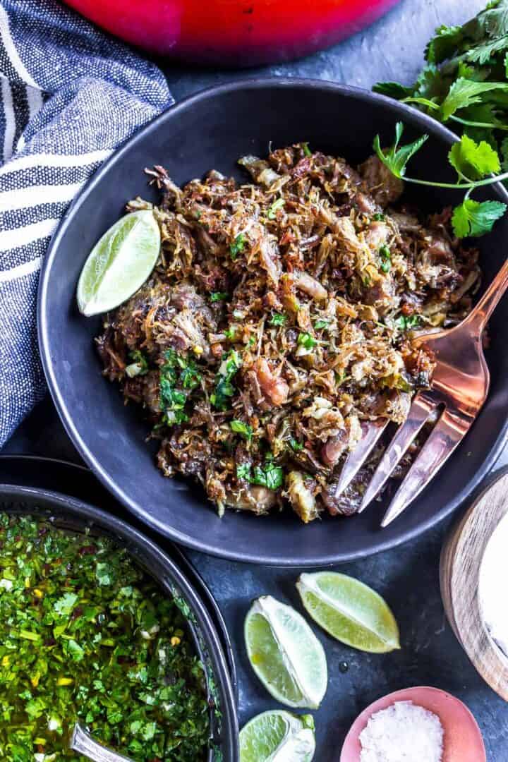 Authentic Carnitas Recipe - carnitas in a bowl with limes