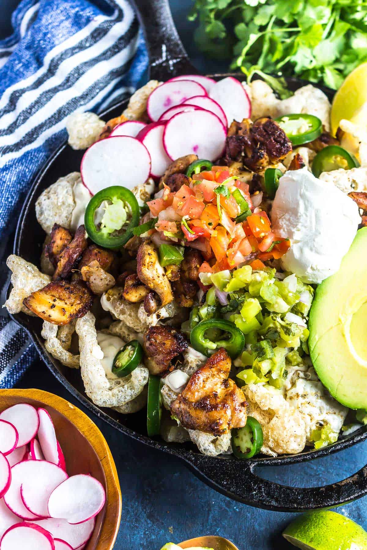 Keto Nachos in a cast iron skillet topped with chicken, cheese, pico de gallo, and more