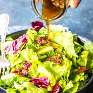 Hot Bacon Dressing being poured over leafy greens.