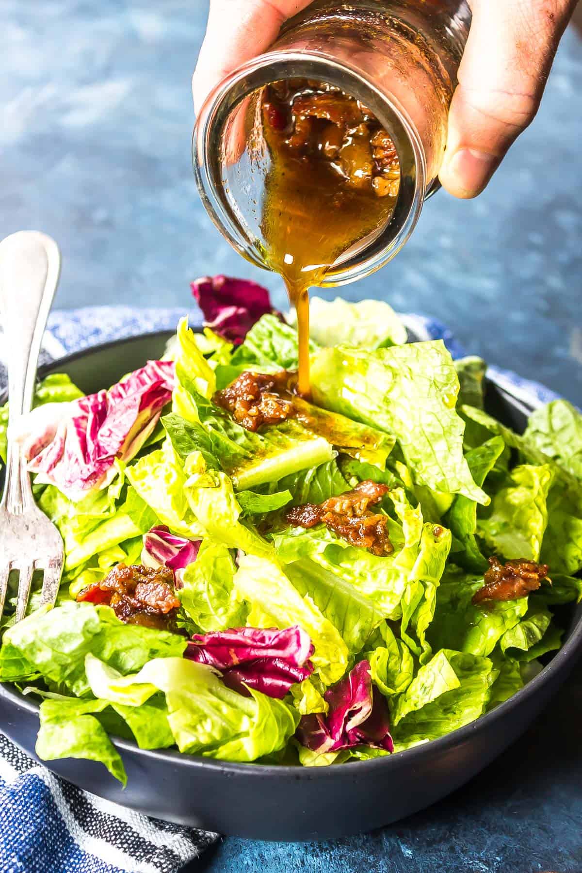 Hot Bacon Dressing being poured over leafy greens.