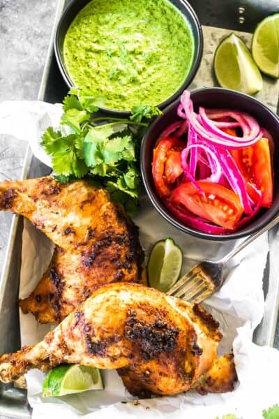 Keto Peruvian Chicken on a platter with salsa and tangy green sauce