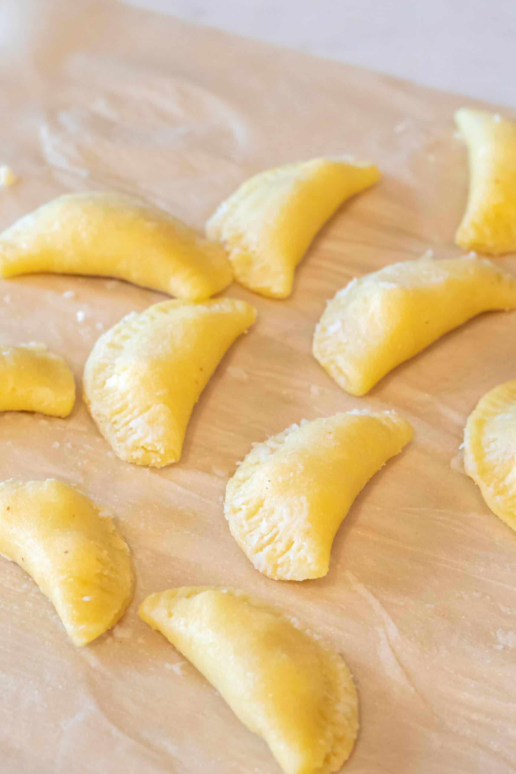 Raw pierogi folded and closed with filling inside.