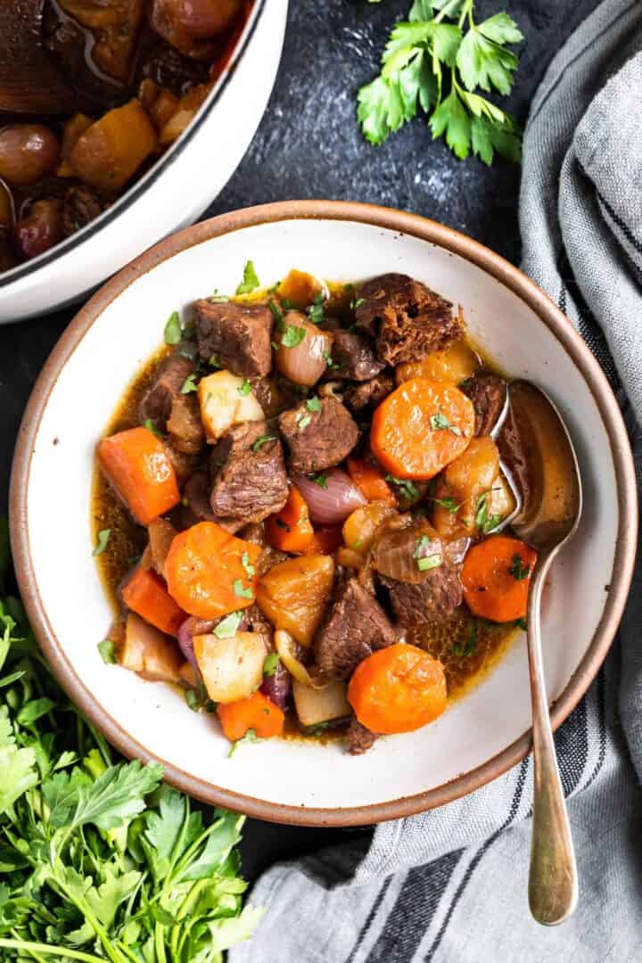 Keto Beef Stew in a bowl with a spoon and a grey tea towel to the side