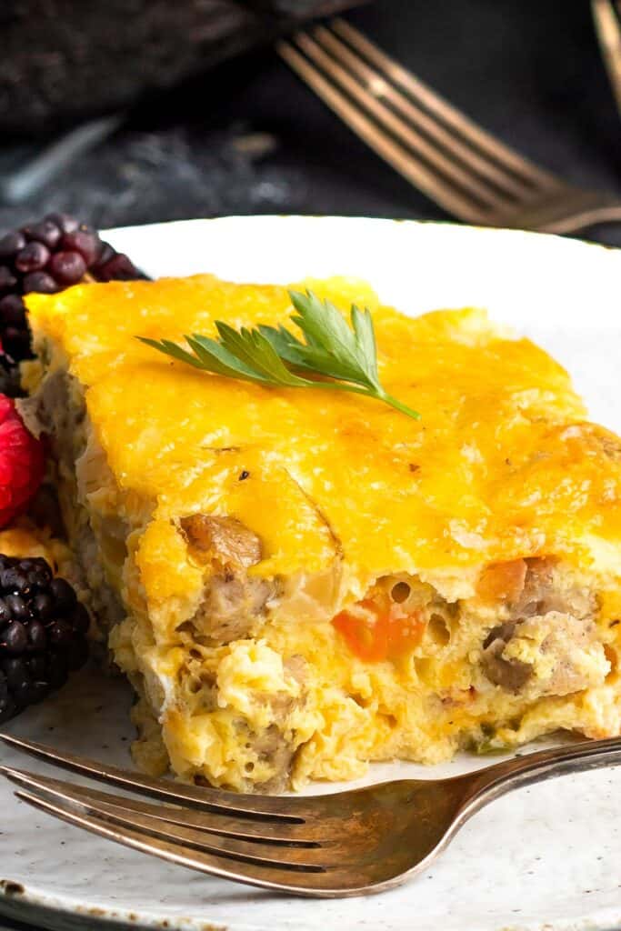 Keto Breakfast Casserole on a white plate with a fork and a mixture of berries