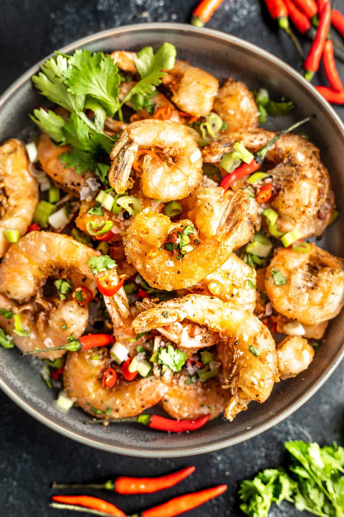 Keto Salt and Pepper Shrimp in a bowl topped with green onions, cilantro, and chiles.