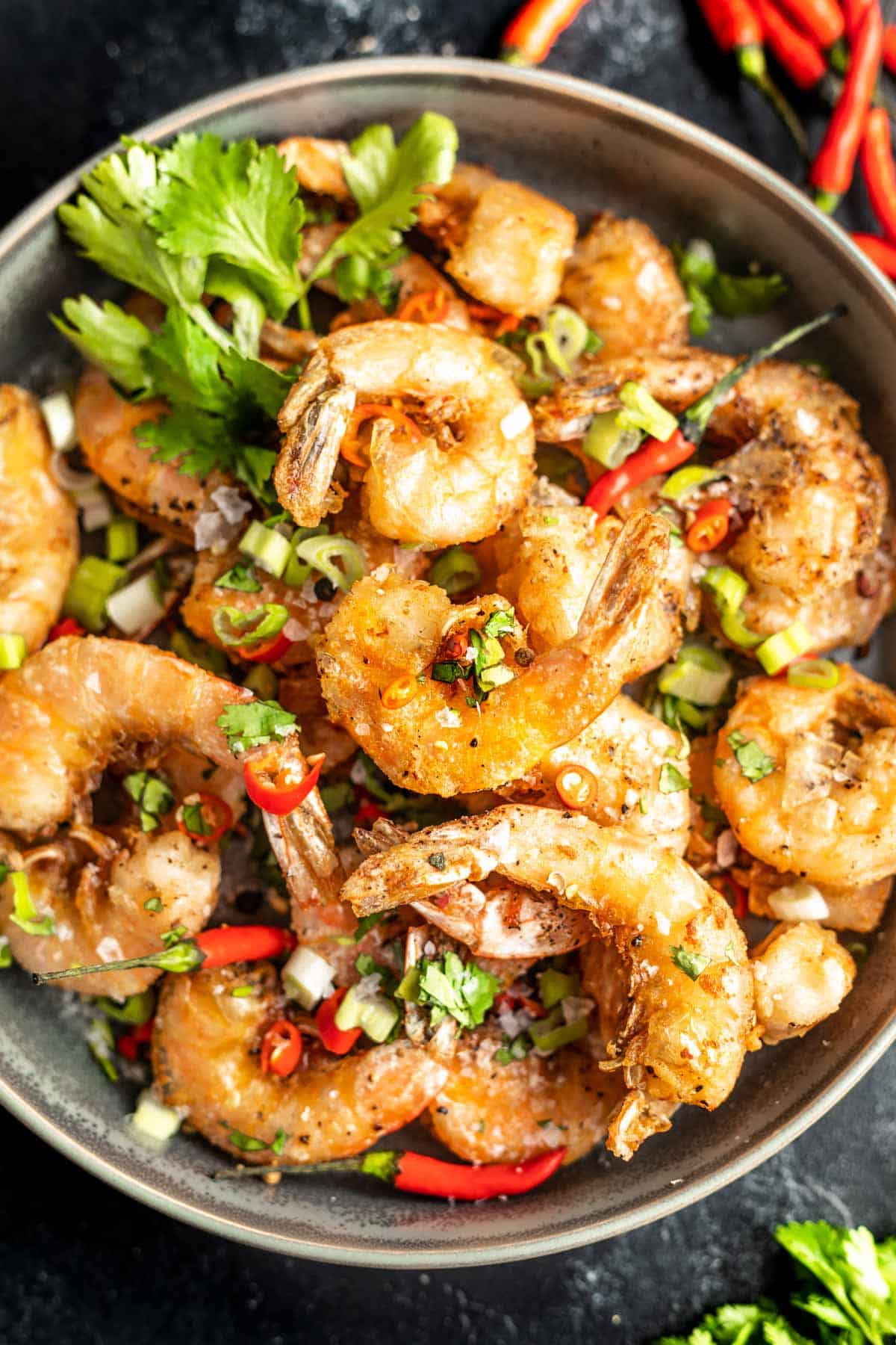 Keto Salt and Pepper Shrimp in a bowl topped with green onions, cilantro, and chiles.