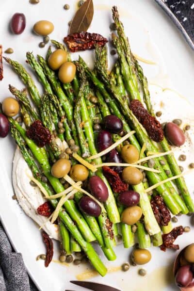 Mediterranean Asparagus - charred lemon garlic asparagus on top of whipped feta and topped with olives, capers, sun-dried tomatoes, and lemon zest.