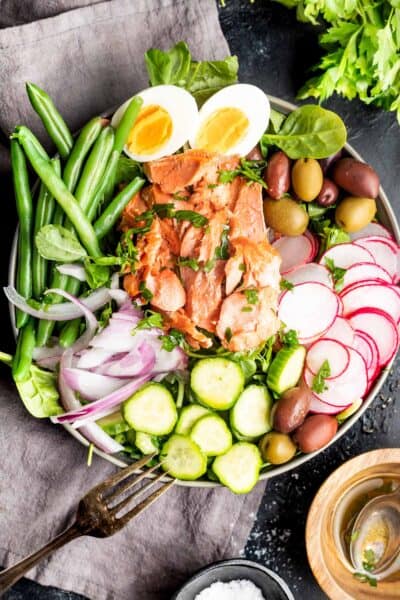 Keto Niçoise Salad in a bowl with a grey tea towel on black background
