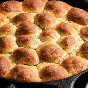 a side shot of a skillet full of seeded keto rolls