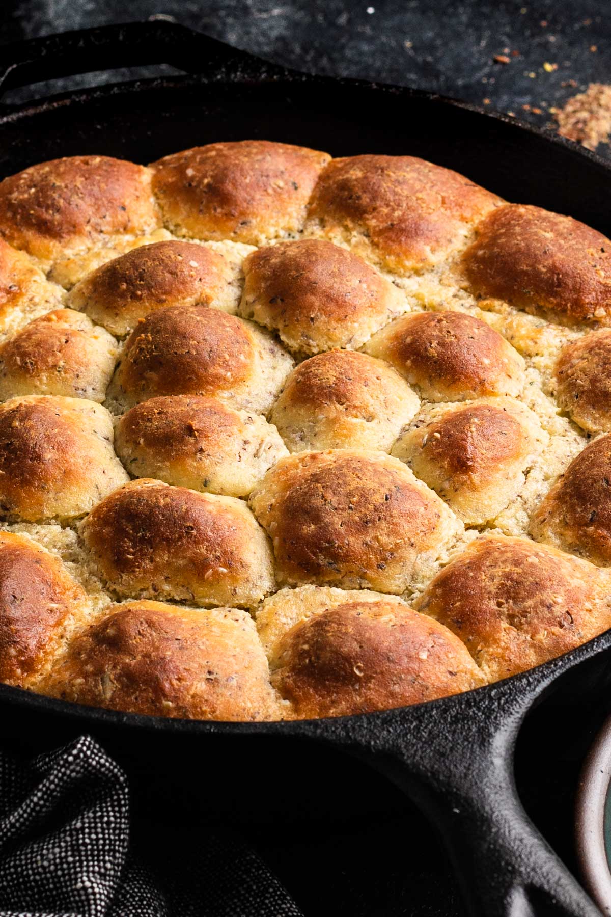 a side shot of a skillet full of seeded keto rolls