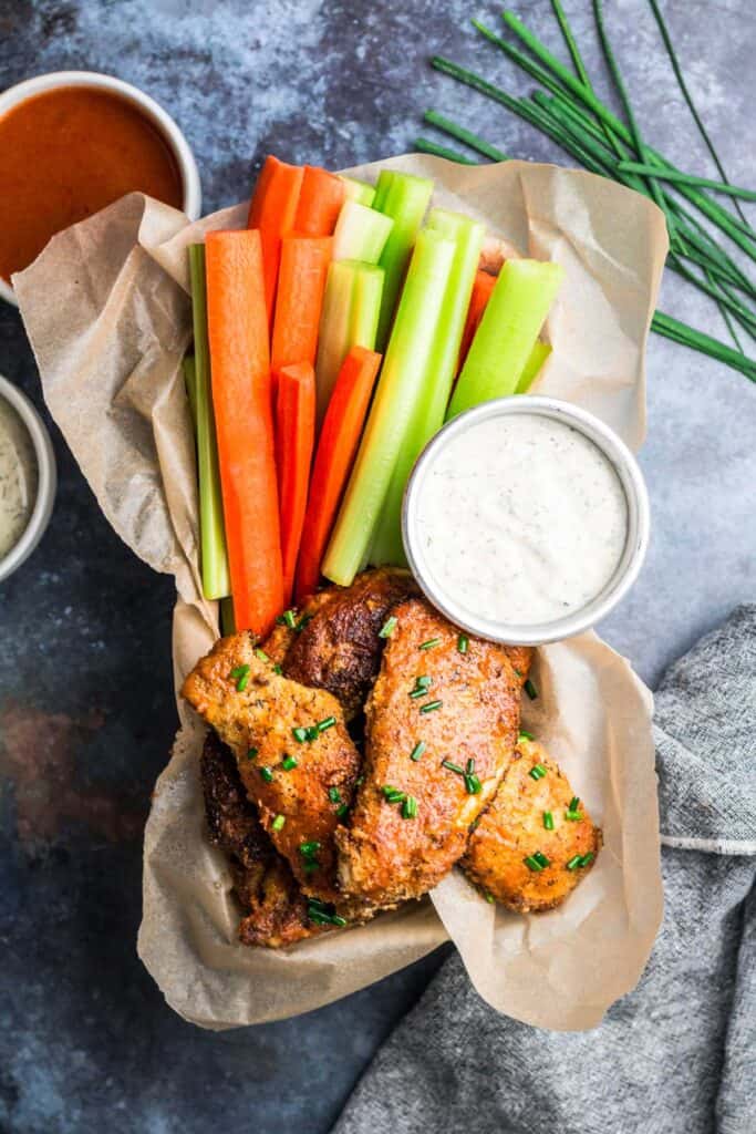 Keto Buffalo Chicken Tenders in a tray with cut fresh veggies and ranch dressing