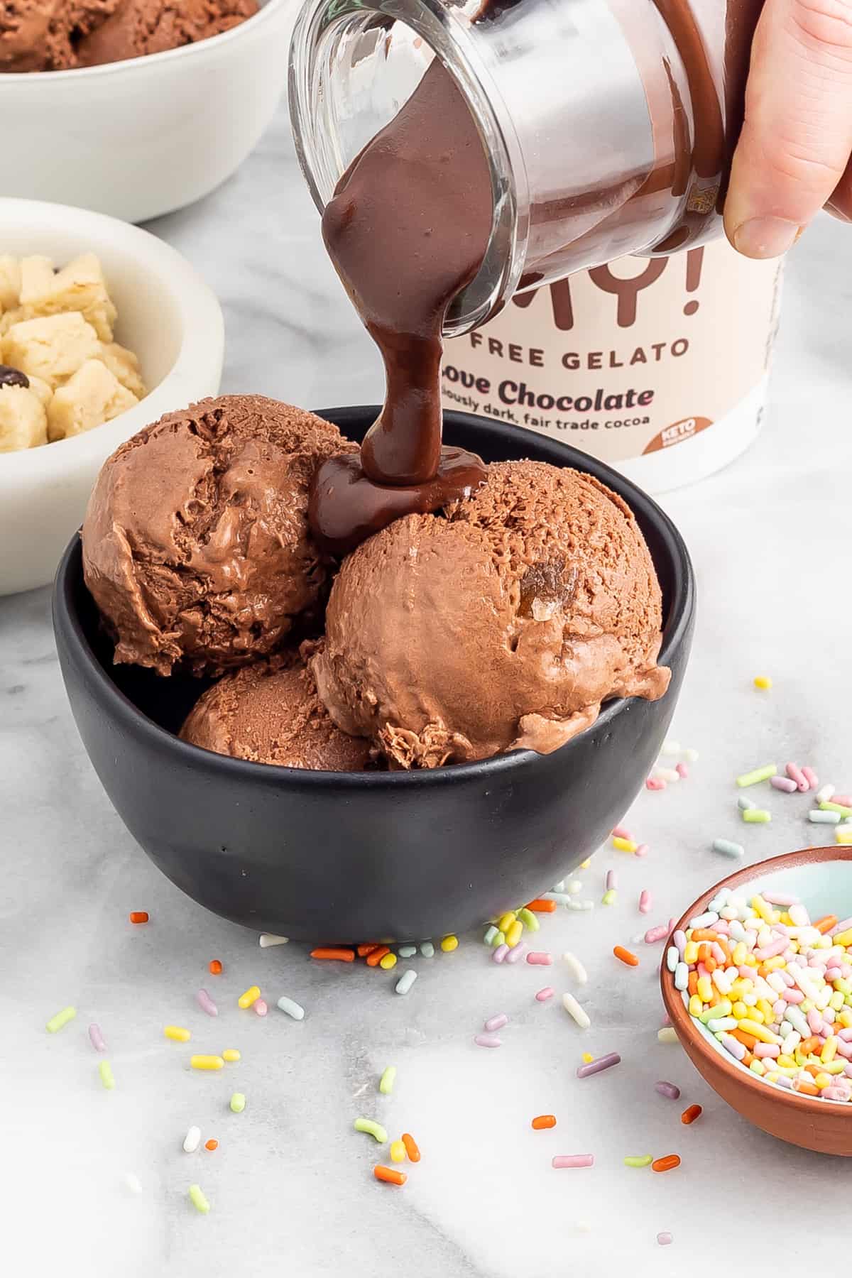 Keto Hot Fudge Sauce being poured over a bowl of chocolate gelato