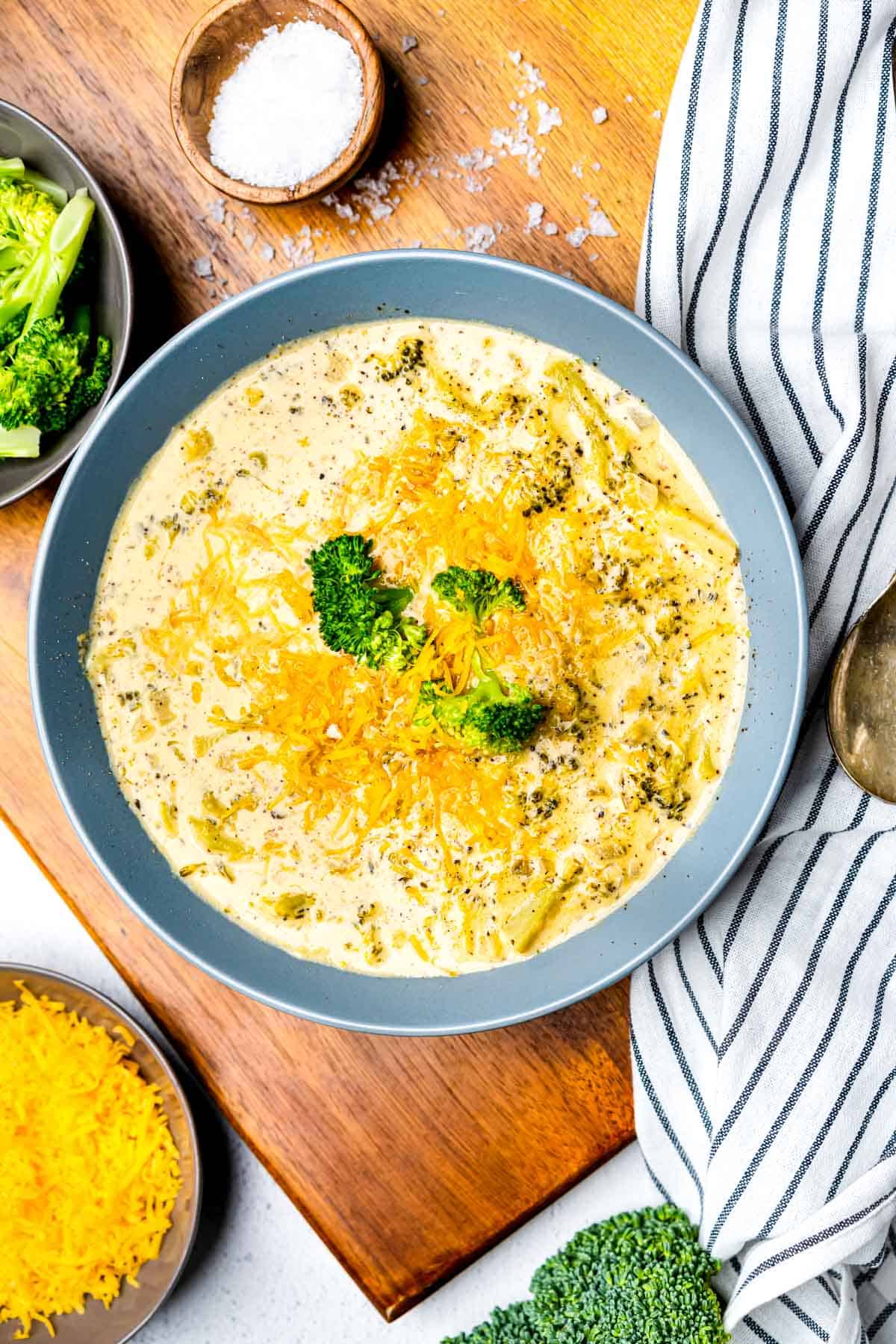 Keto Broccoli Cheese Soup in a blue bowl on a wooden cutting board